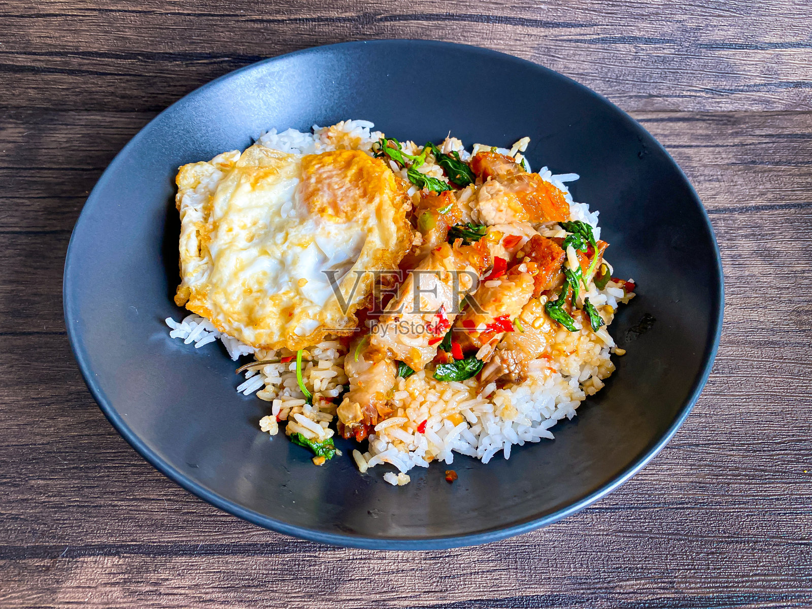 米饭上面有脆皮五花肉,泰国罗勒和煎蛋照片摄影图片