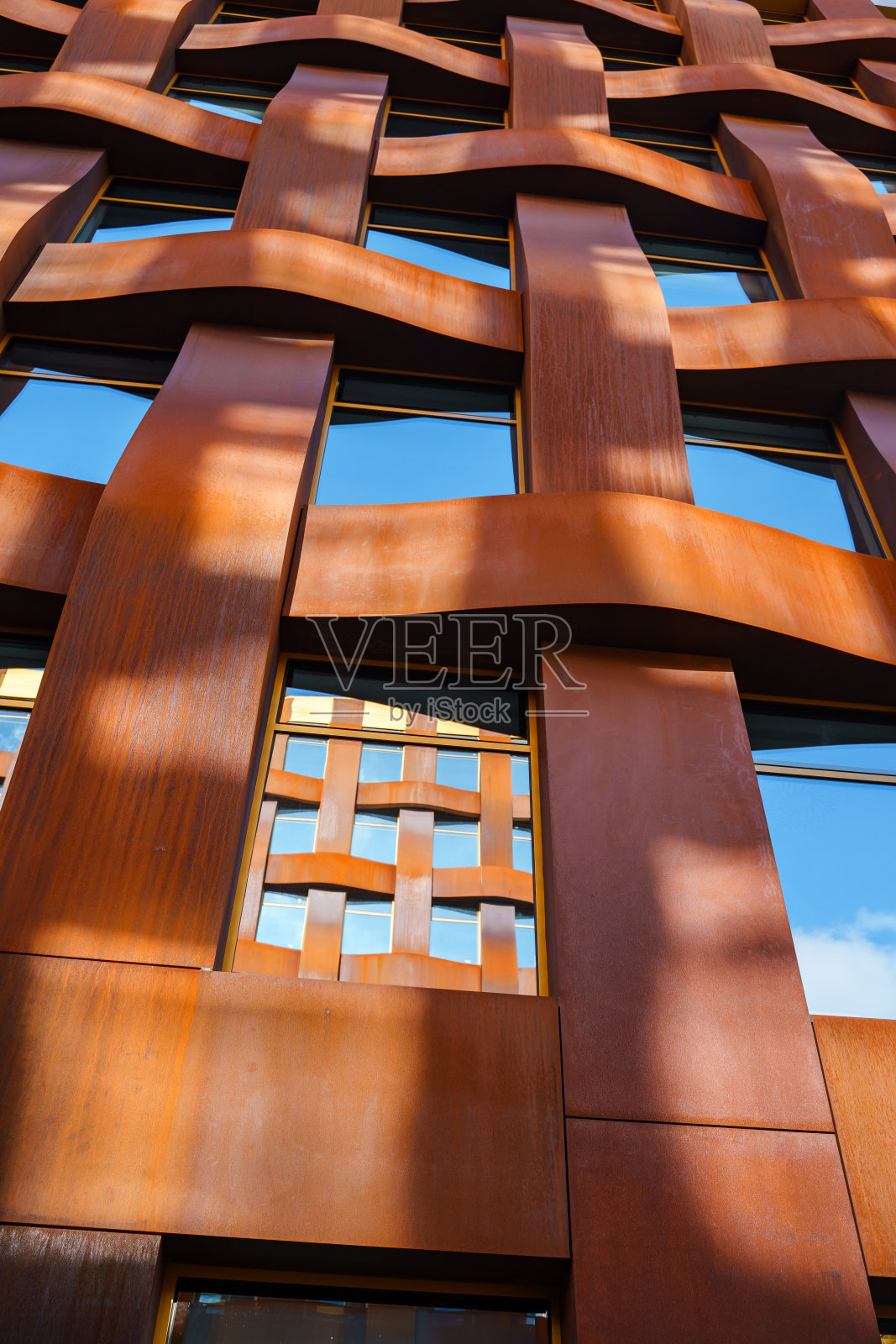 这是一栋现代商业建筑的棕色立面,网格图案衬着蓝天。照片摄影图片