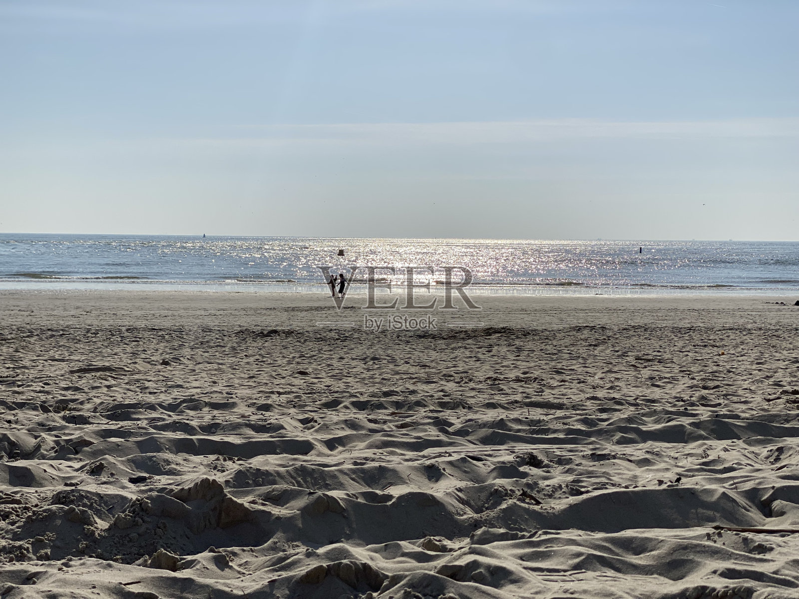 两个孩子在阳光和蓝天的沙滩上照片摄影图片