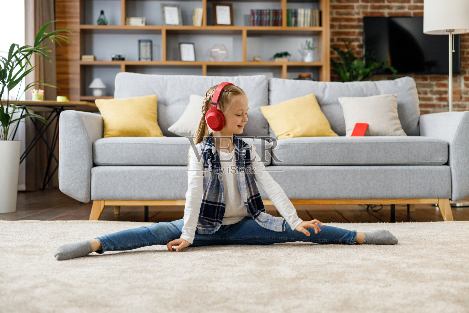 微笑活泼的小女孩坐在家里地毯上的麻绳上。一个小芭蕾舞演员的家庭训练。孩子们积极健康的休闲照片摄影图片