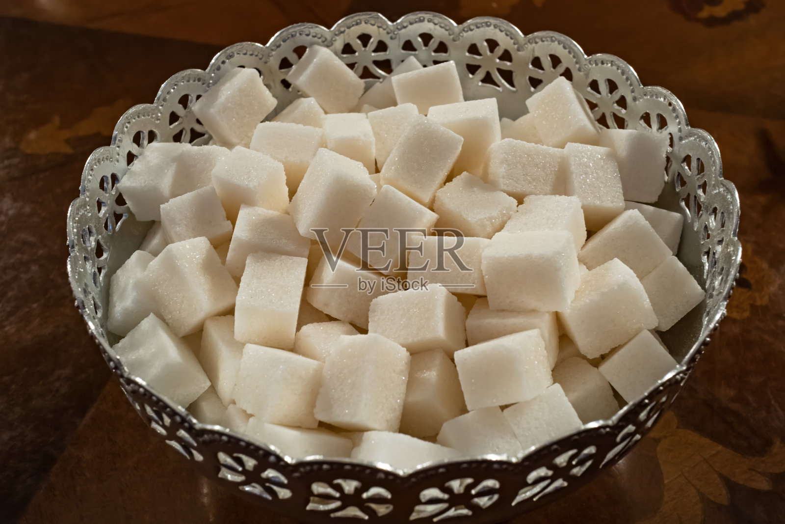 桌上的金属碗里放着方糖。天然精制压糖特写照片摄影图片