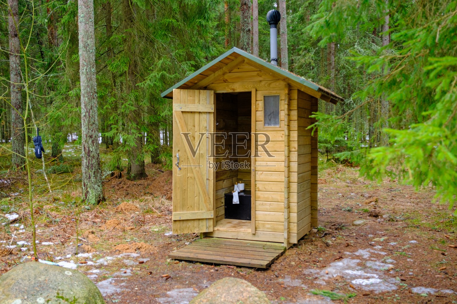 森林里的木制户外厕所,有一个敞开的门。卫生纸卷。照片摄影图片