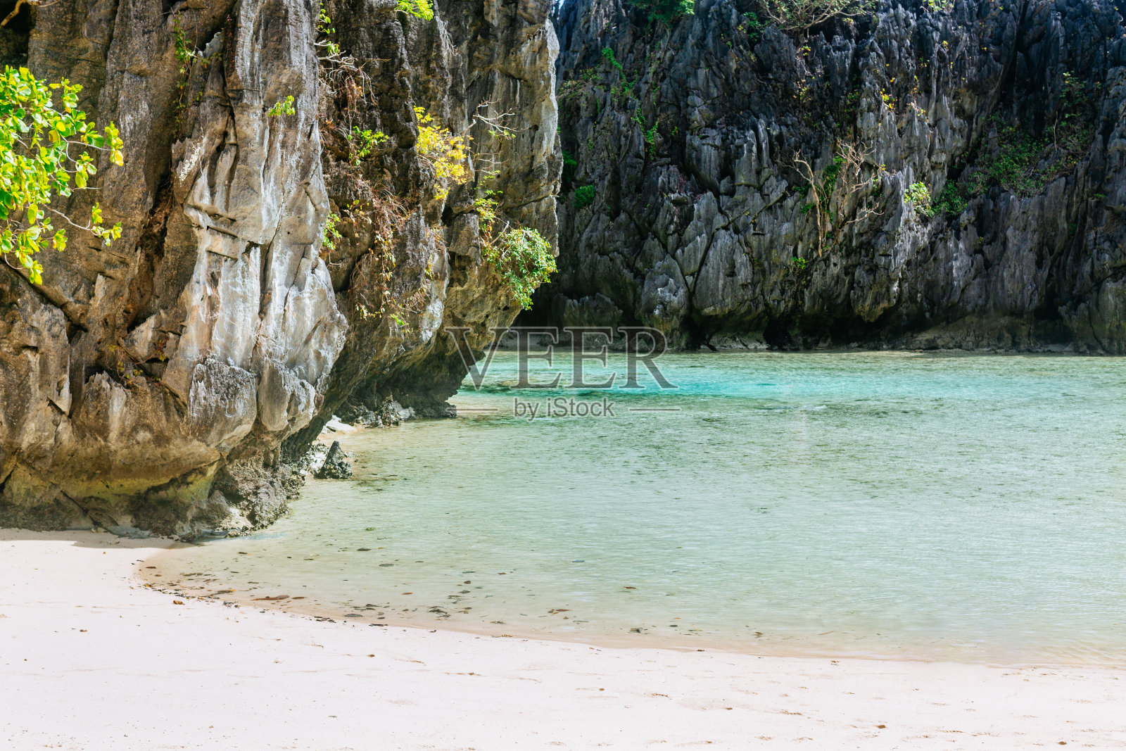 阳光明媚的爱妮岛。一个清澈碧绿的海湾,周围是陡峭的悬崖。照片摄影图片