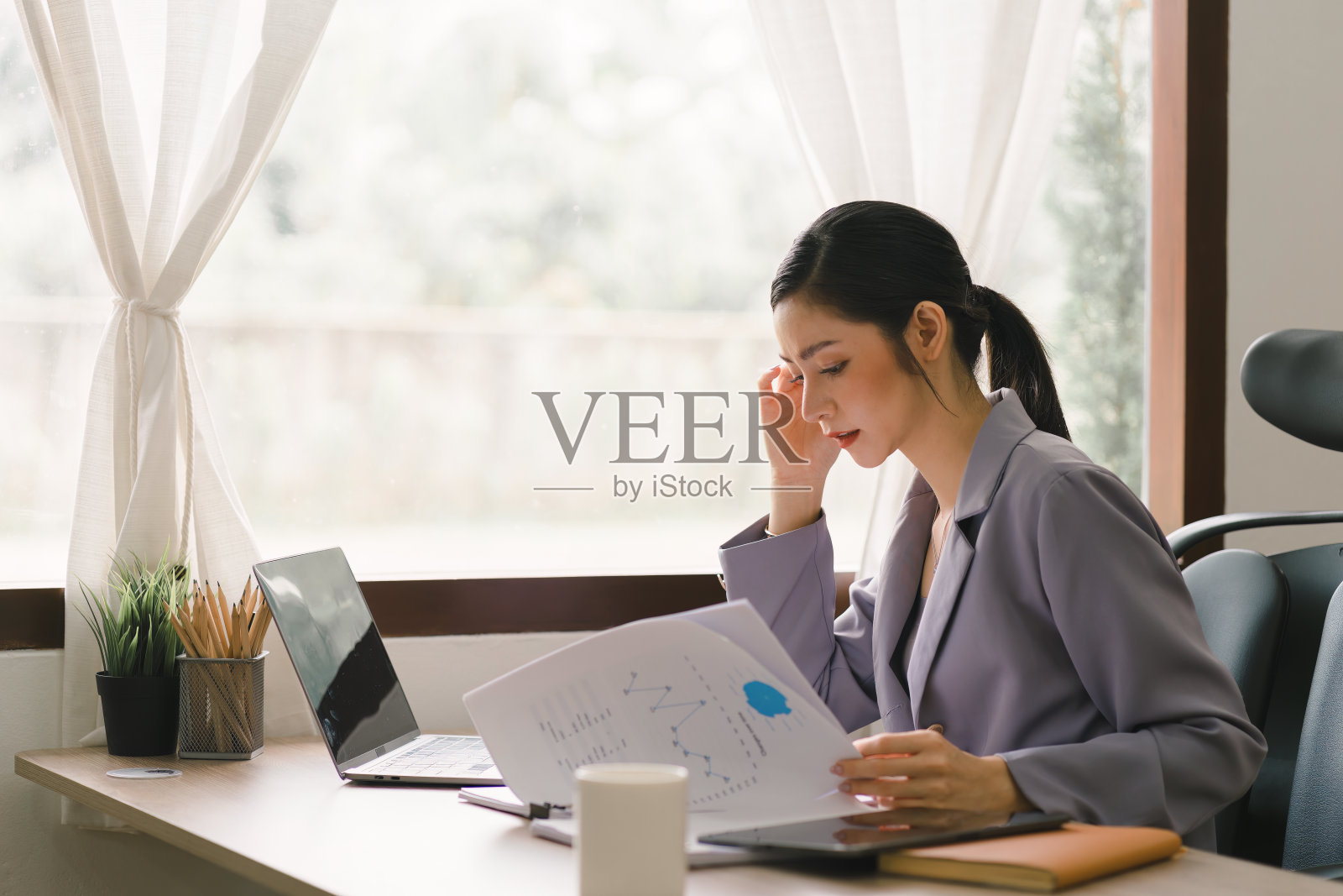 创业公司的千禧一代女商人在家里办公室用笔记本电脑管理她的业务。照片摄影图片