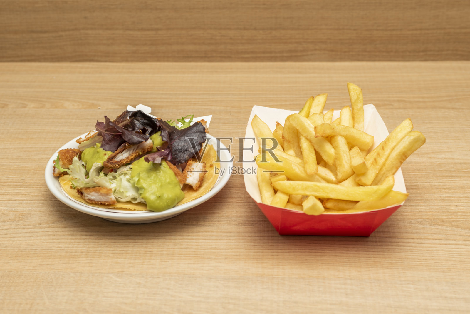 墨西哥墨西哥人墨西哥卷饼,有烤熟的鸡肉、牛油果奶油和生菜叶,还有一份油炸土豆,放在木桌上照片摄影图片