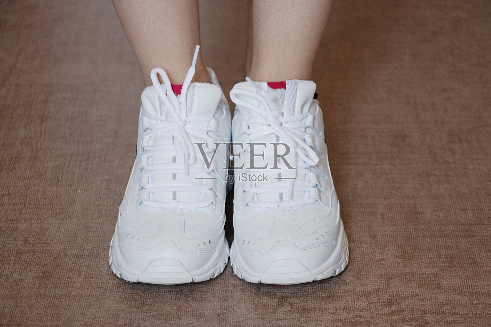 一个站在地板上的女孩裤脚里塞着一双白色运动鞋照片摄影图片
