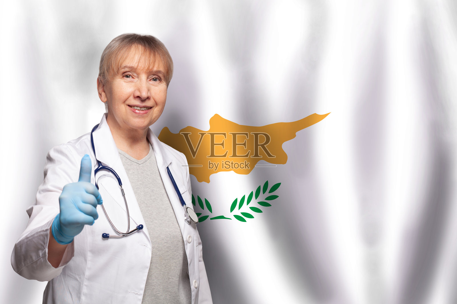 塞浦路斯面带微笑的成熟女医生手持听诊器,背景是塞浦路斯国旗照片摄影图片