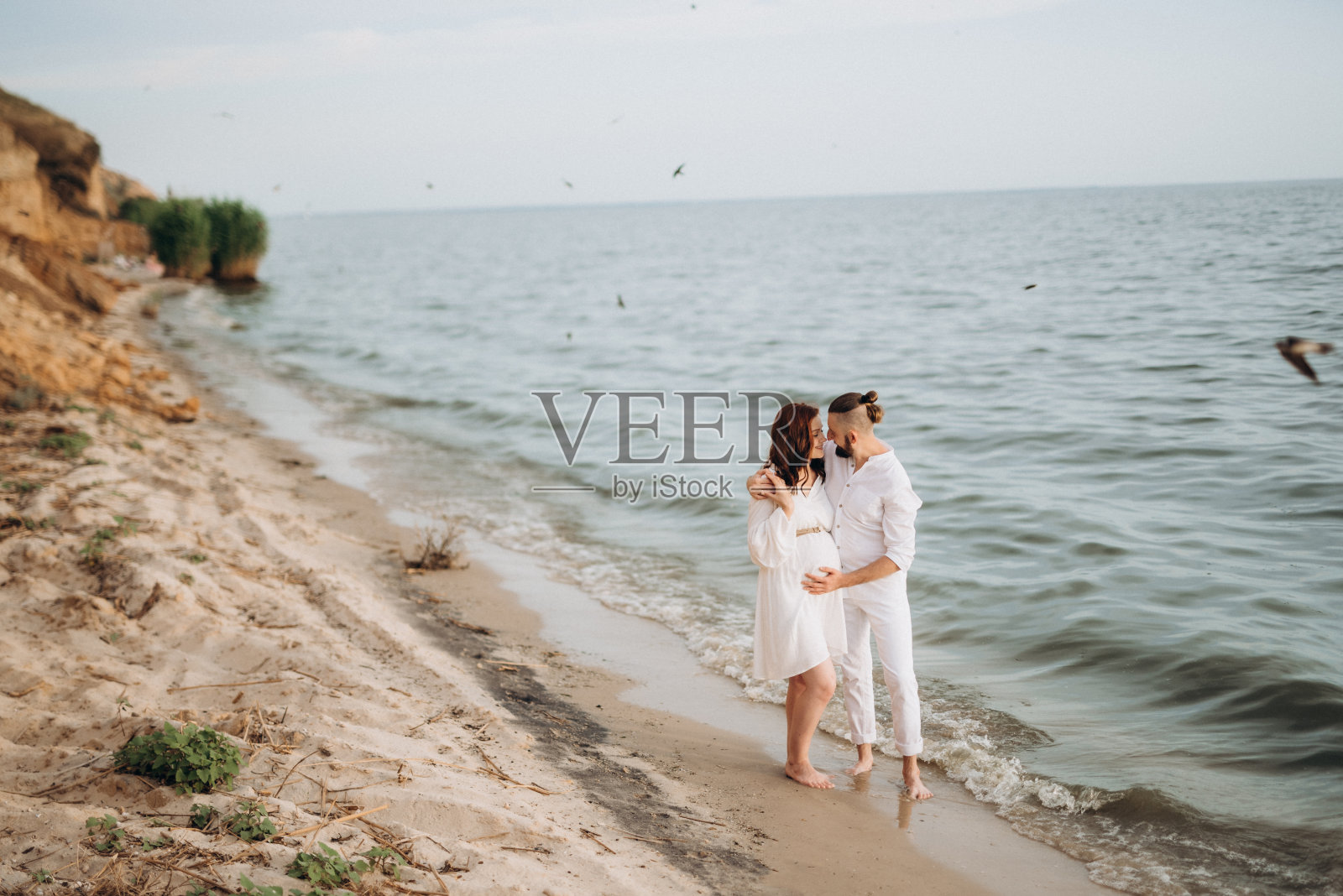 一个男人和一个穿白衣的女孩在海边照片摄影图片