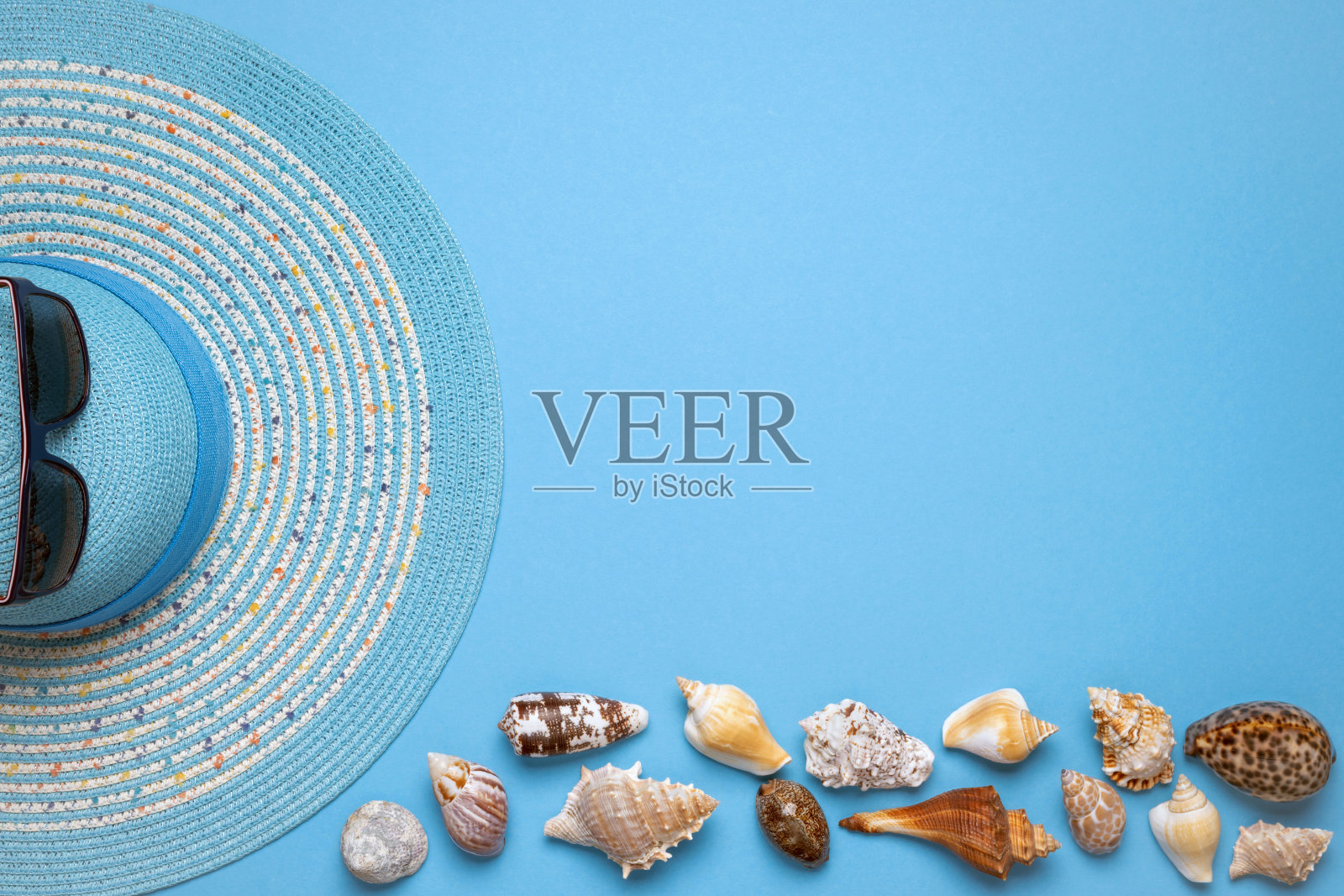 夏天和度假的公寓里躺着一个美丽的蓝色条纹女人草帽和太阳镜在蓝色的背景。照片摄影图片