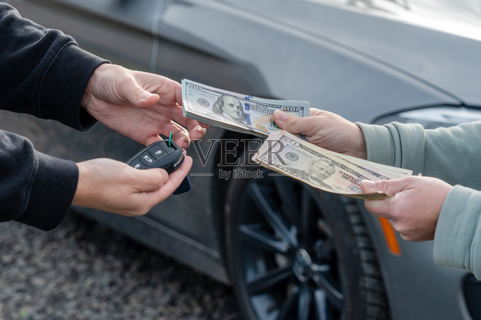 交易购买或租赁汽车的概念。一只手拿着车钥匙,另一只手给钱。照片摄影图片