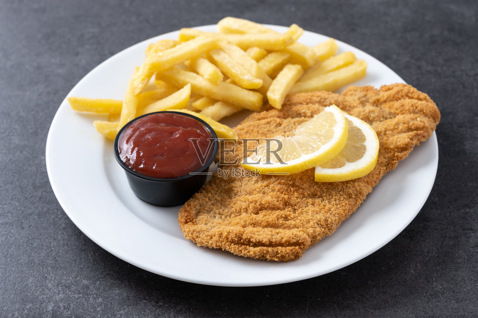 黑色石板表面的维也纳炸肉排配炸土豆。典型的维也纳食物照片摄影图片