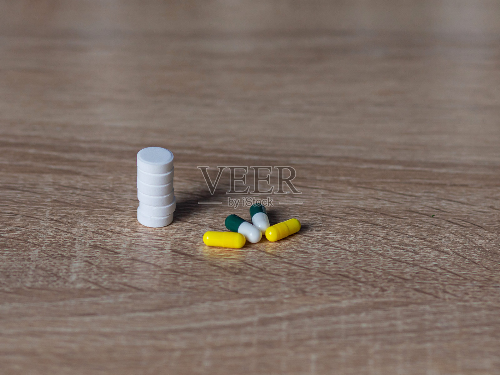 白色和彩色药片放在木桌上。健康的一天。医生和药物。服用维生素。治疗疾病。照片摄影图片