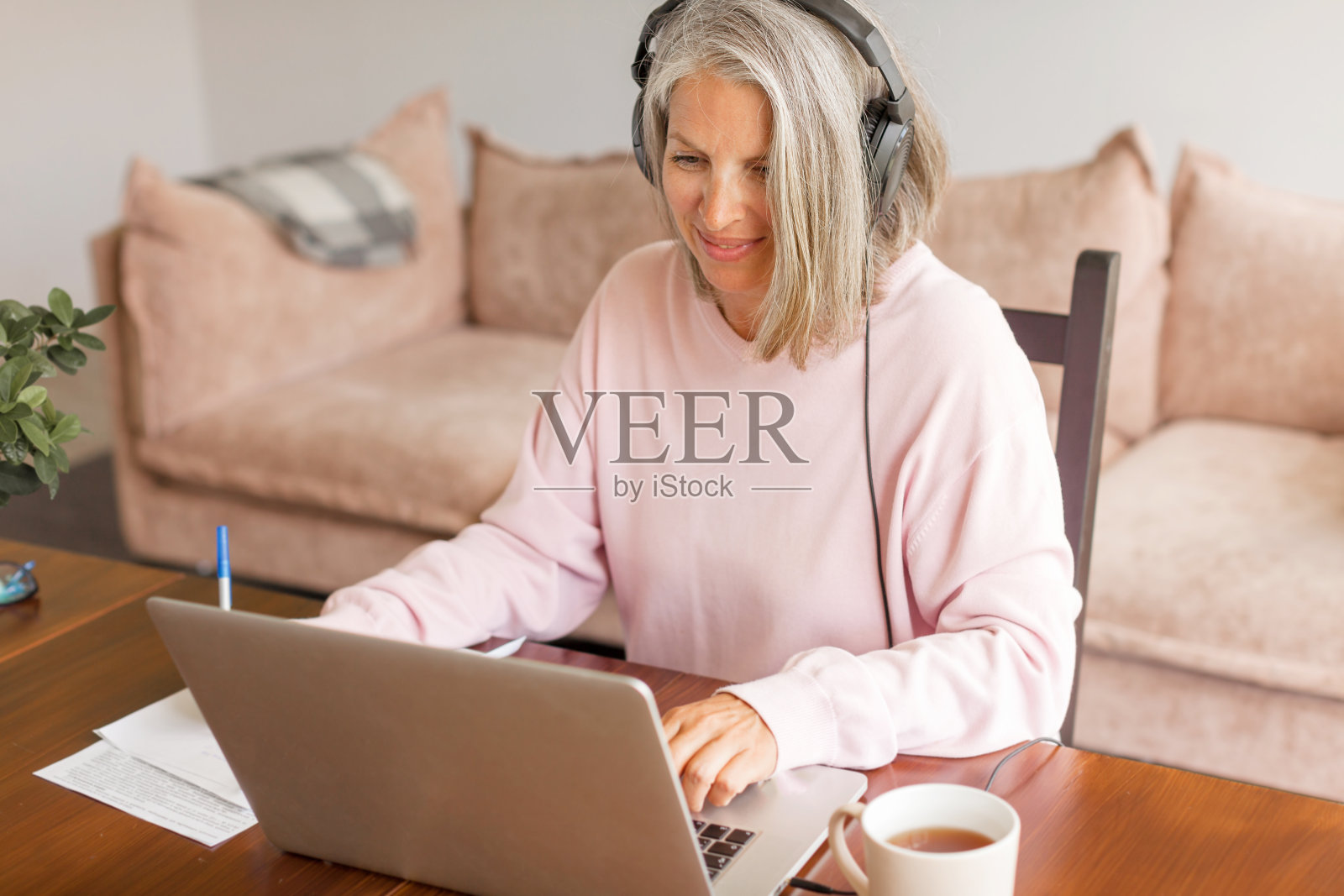 中年女商人坐在笔记本电脑后面用耳机照片摄影图片