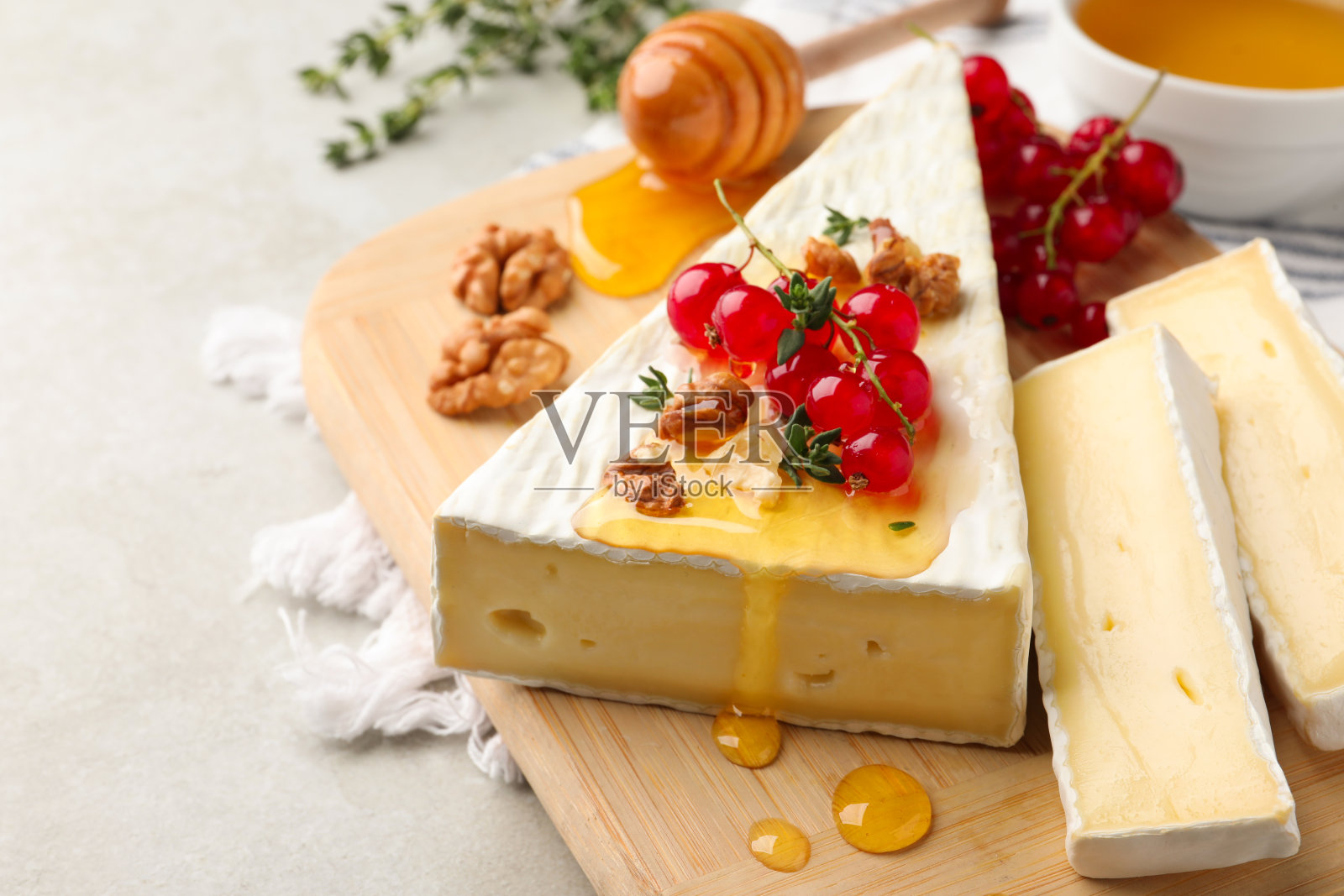 布里奶酪配红醋栗,核桃和蜂蜜,在浅色的桌子上,特写照片摄影图片