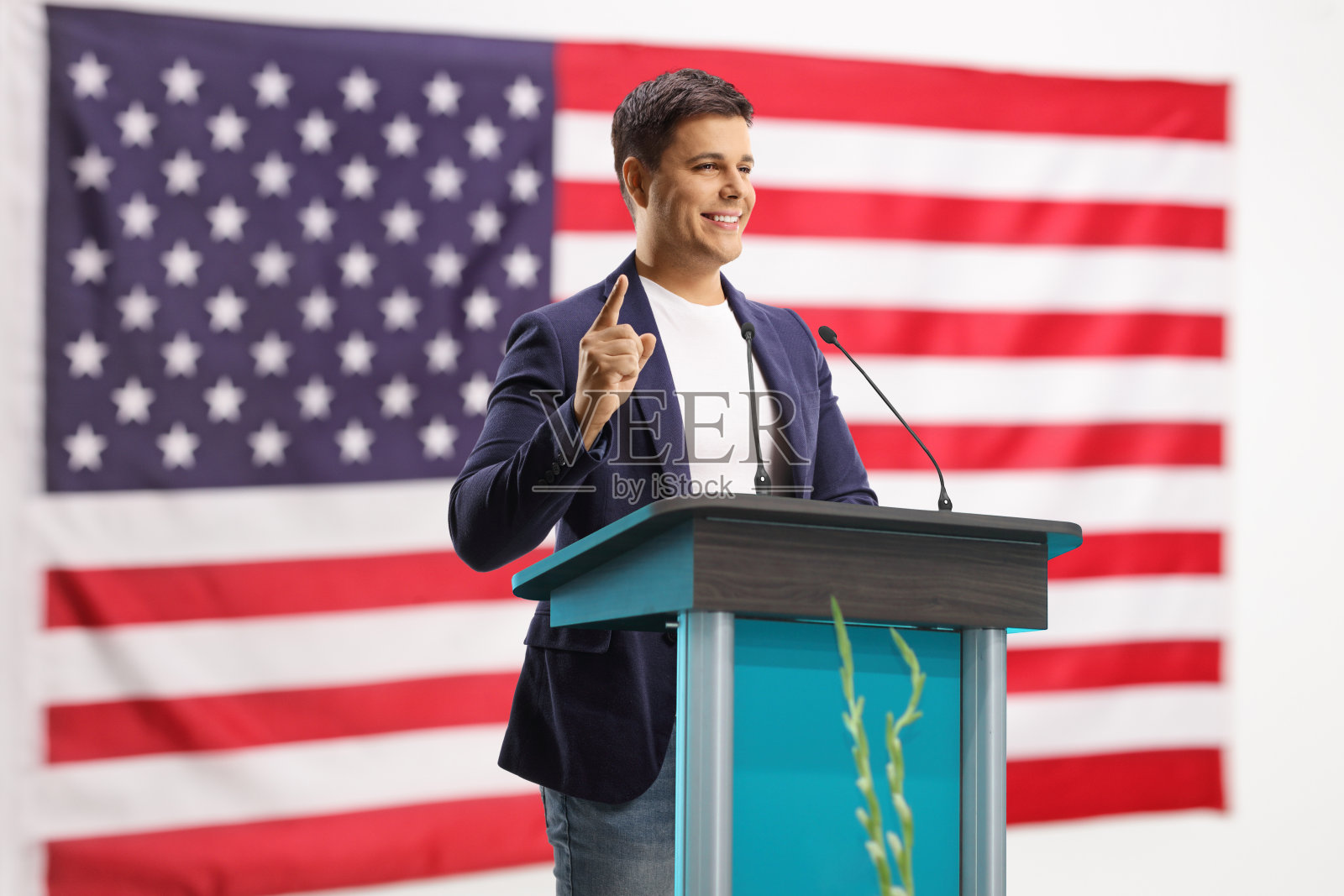 一个年轻人站在讲台上演讲,身后是美国国旗照片摄影图片