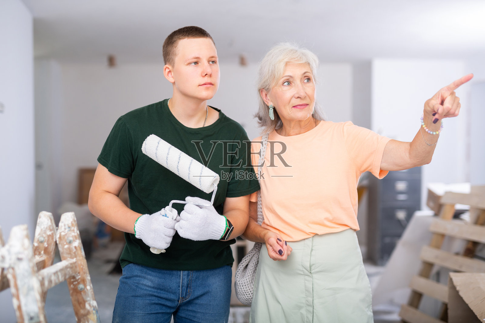 一位年长的妇女在建筑工地与十几岁的男孩讨论工作细节照片摄影图片