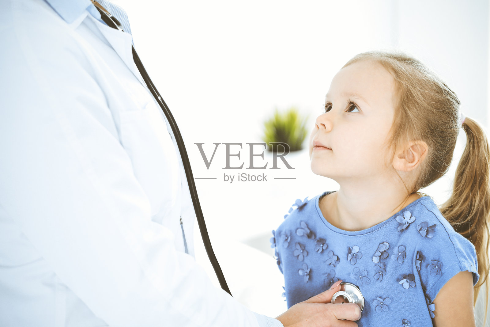 医生用听诊器检查一个小女孩。在例行体检中开心微笑的孩子。医学和保健概念照片摄影图片