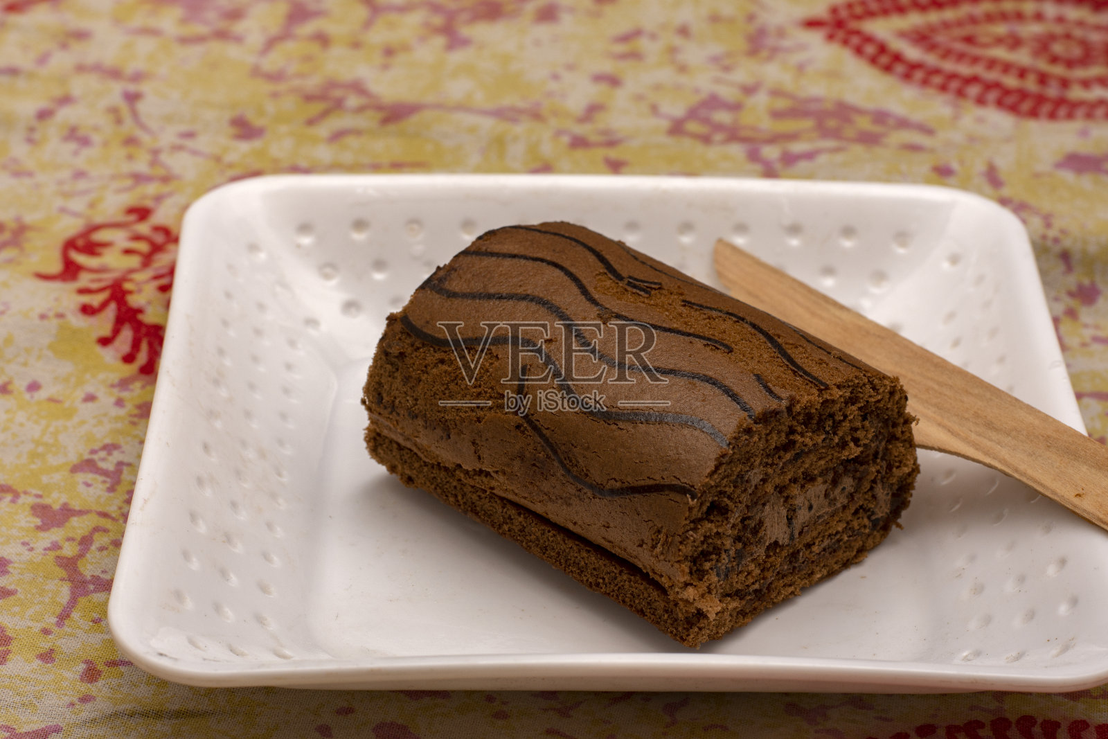 白色盘子里的巧克力瑞士卷蛋糕。照片摄影图片