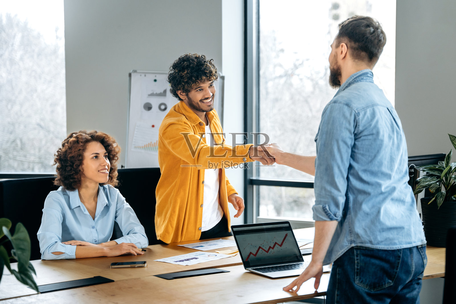 商务人士签订合作协议,达成交易。握手。友好的成功男性合伙人在会议室里互相握手,微笑,对成功的谈判感到满意照片摄影图片