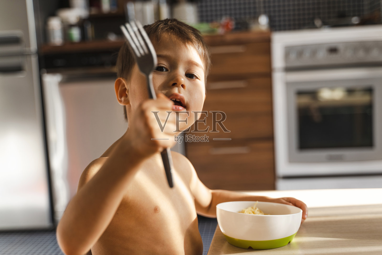 可爱的小男孩在吃他最喜欢的食物——意大利面照片摄影图片