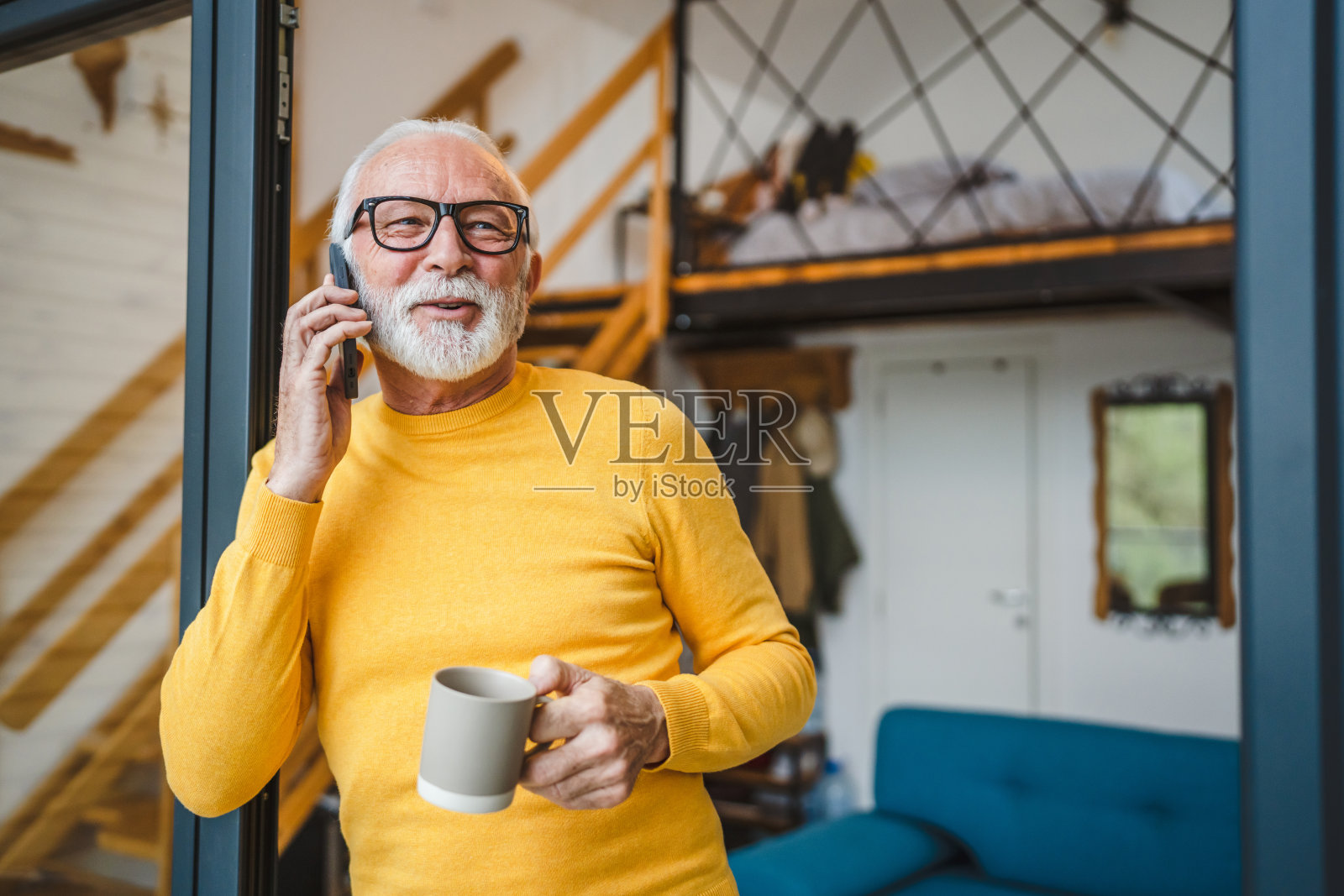 一位老人白天站在小房子门口使用智能手机照片摄影图片