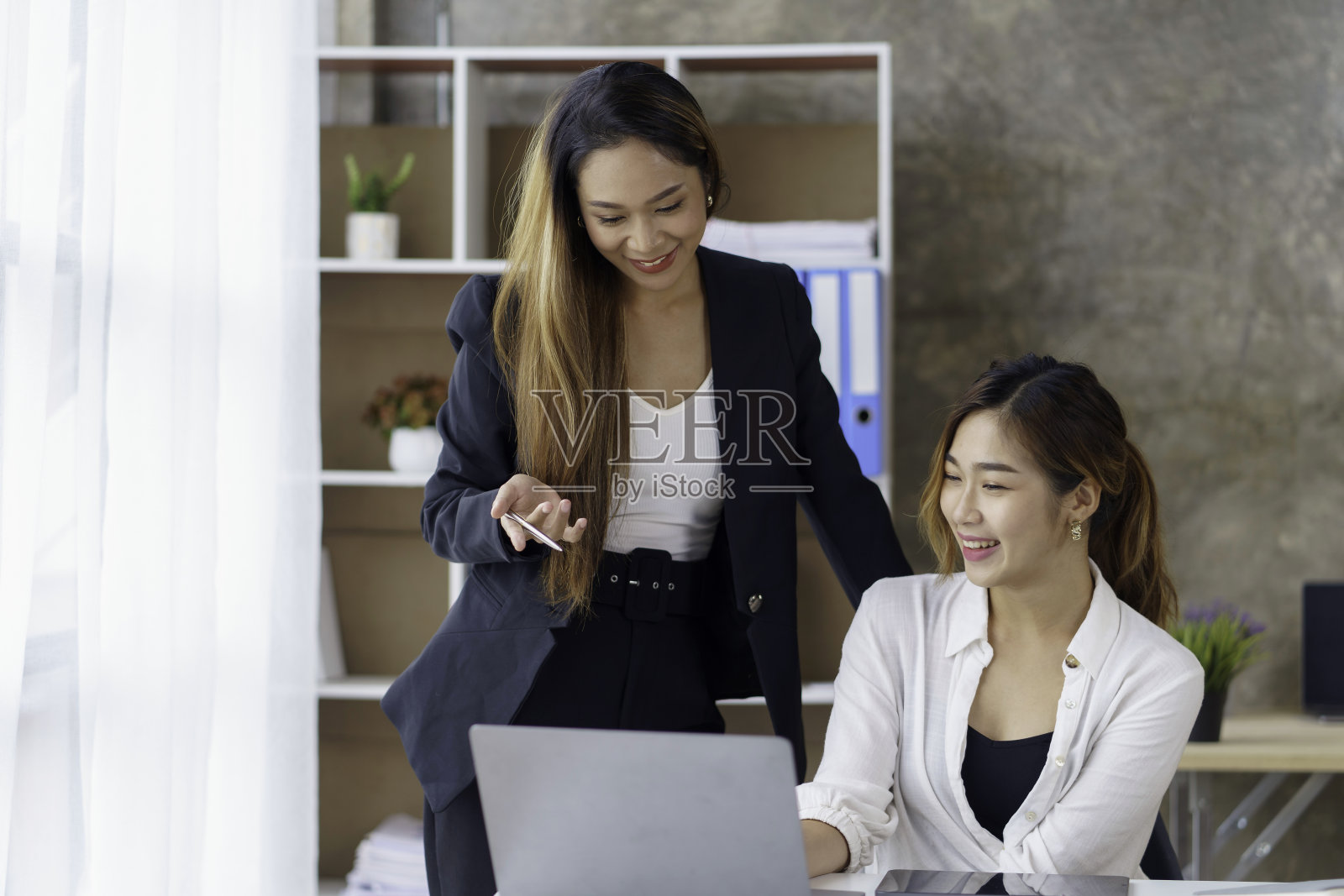 两位年轻的亚洲商人在办公室里用笔记本电脑讨论投资项目和计划策略。照片摄影图片