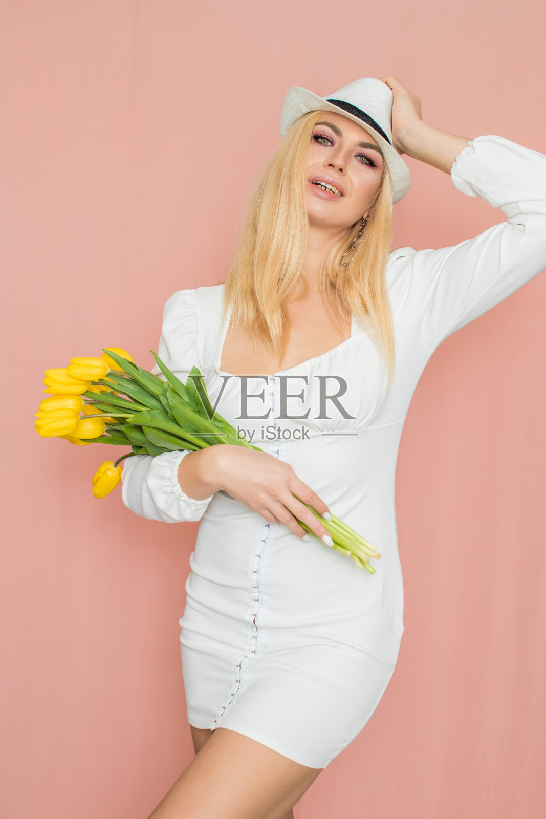 穿白衣服戴白帽子的女人手里拿着黄色的郁金香照片摄影图片