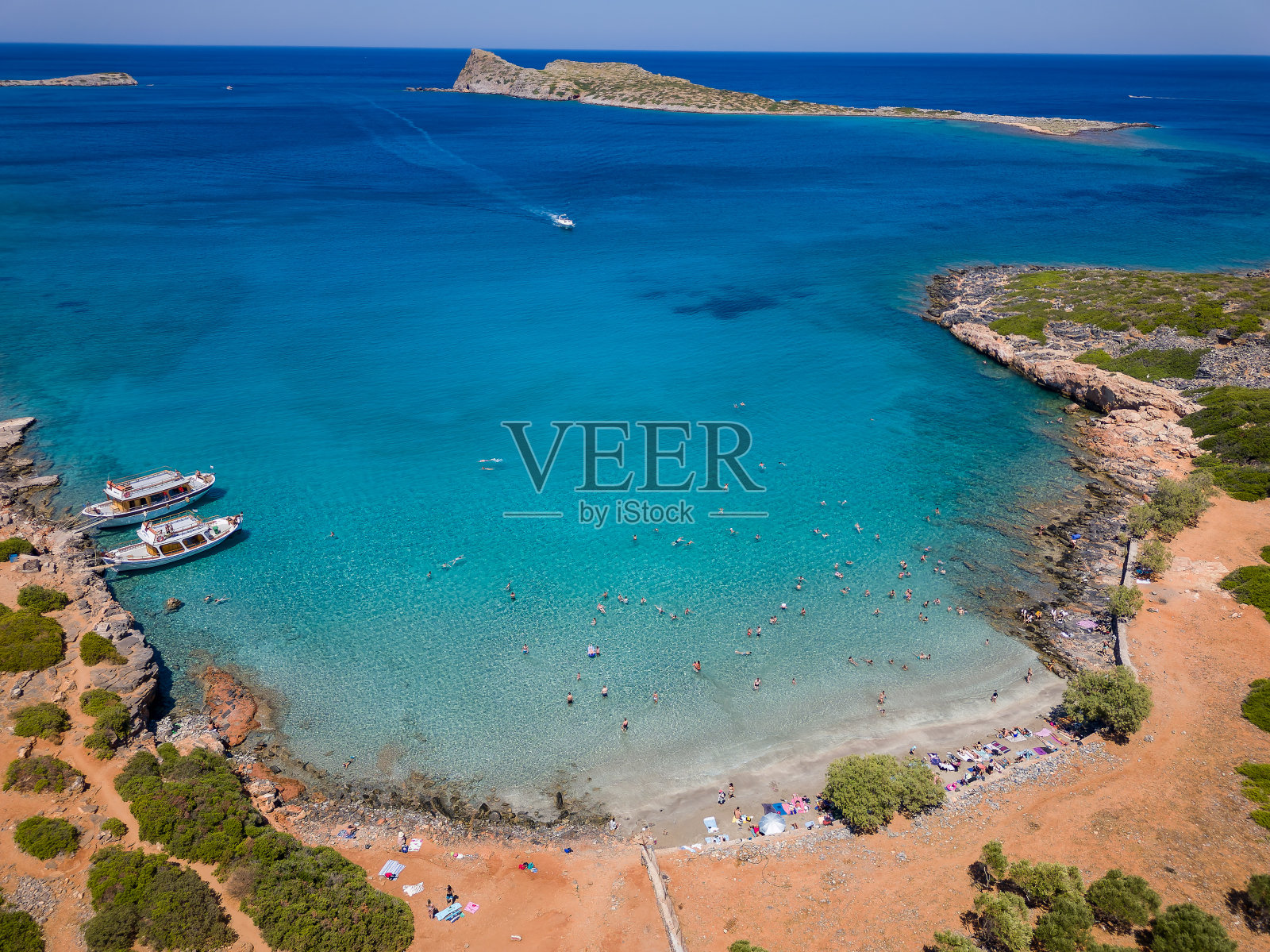 克里特岛(Kolokitha)炎热的夏日里,游泳者在一个小海滩和清澈的海洋上鸟瞰。照片摄影图片