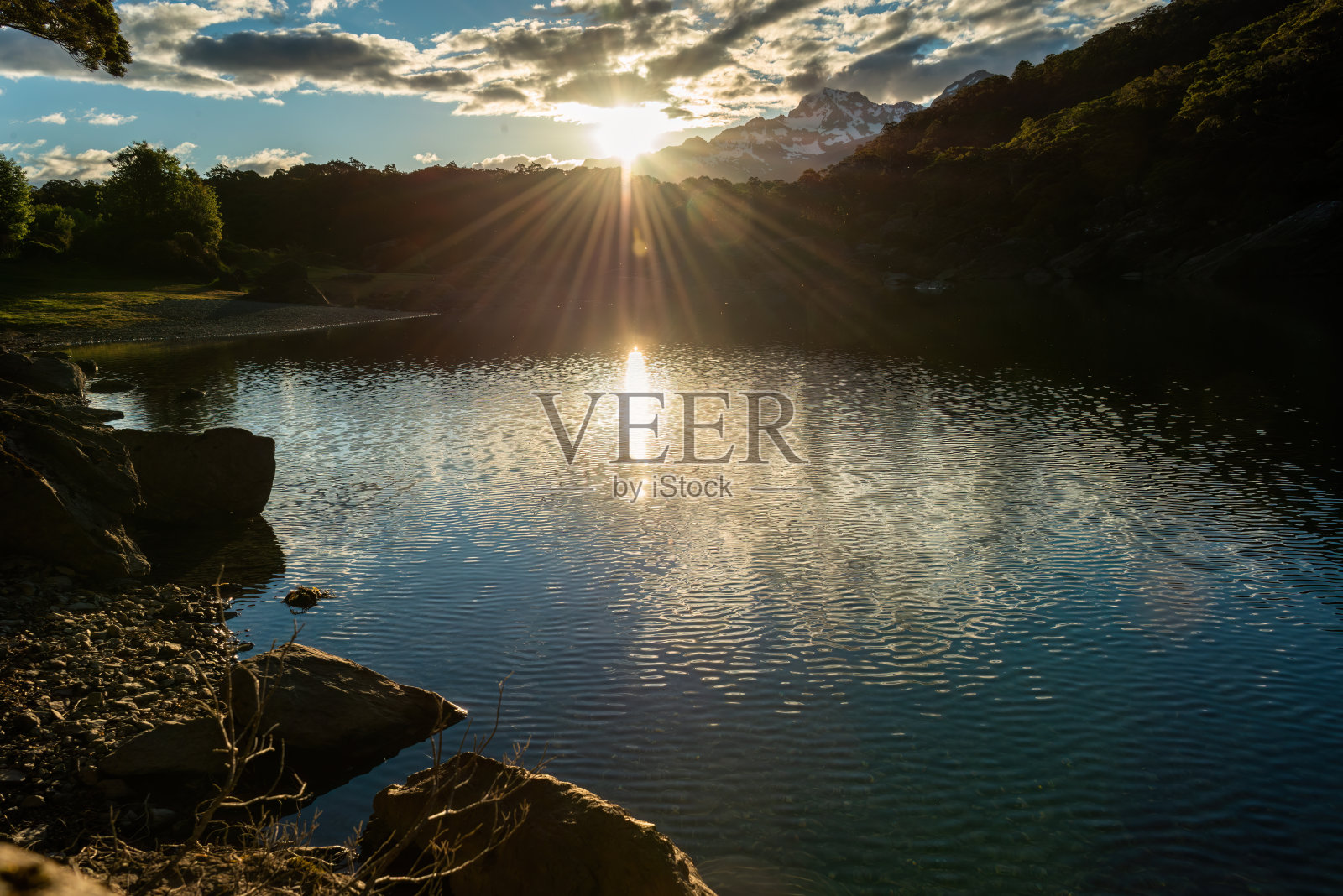 日落时路特本赛道上的麦肯齐湖。太阳星光透过云层闪耀。南岛。照片摄影图片