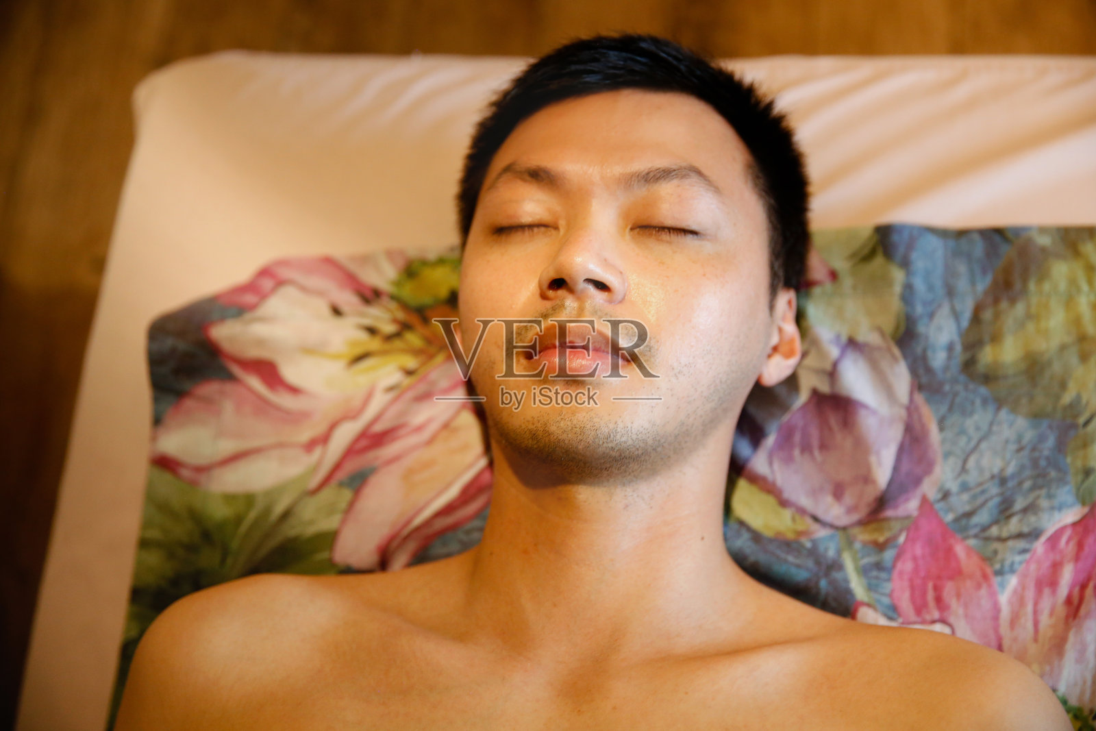 亚洲男人闭着眼睛躺在水疗房里照片摄影图片