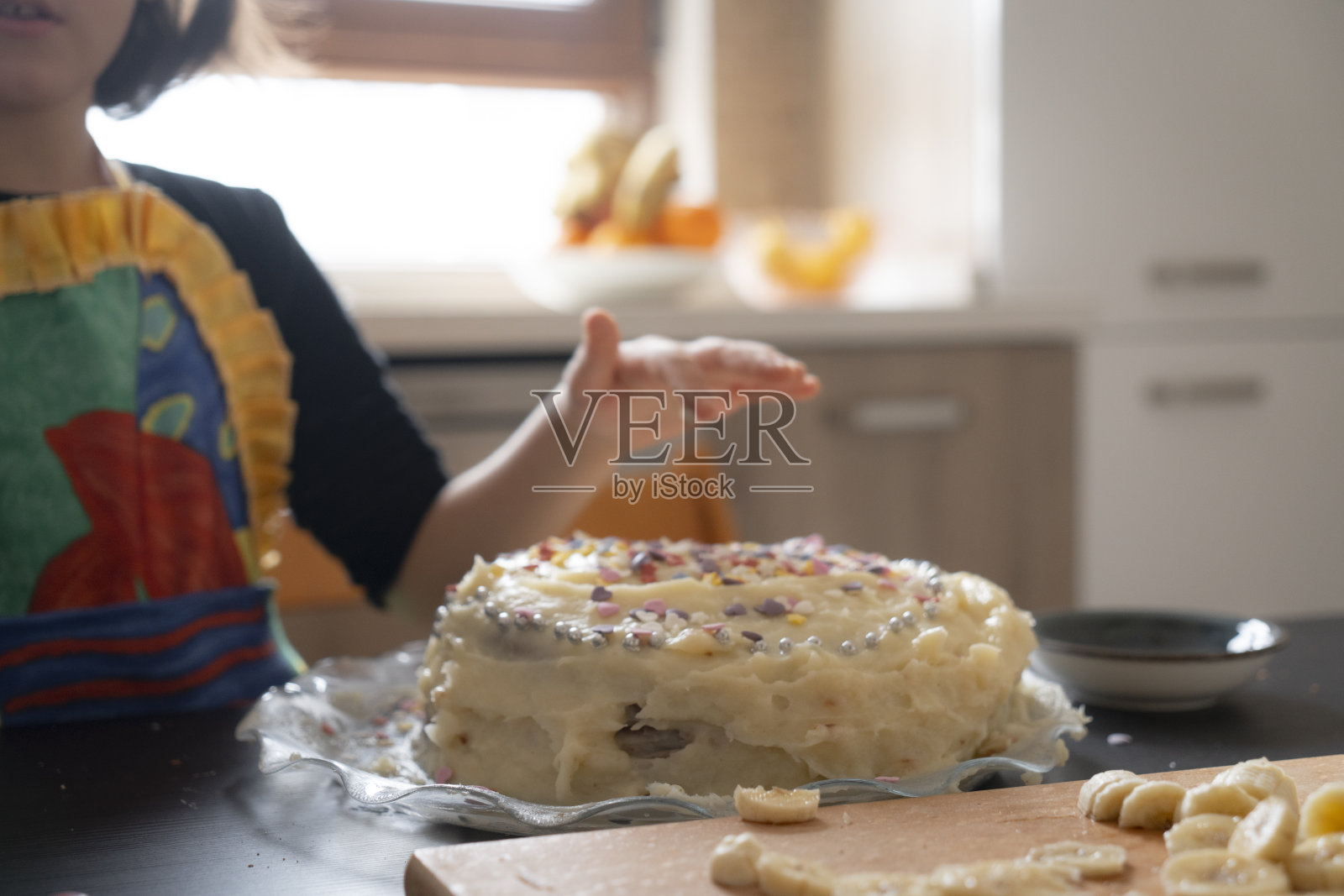 小女孩在生日蛋糕上撒糖屑。照片摄影图片