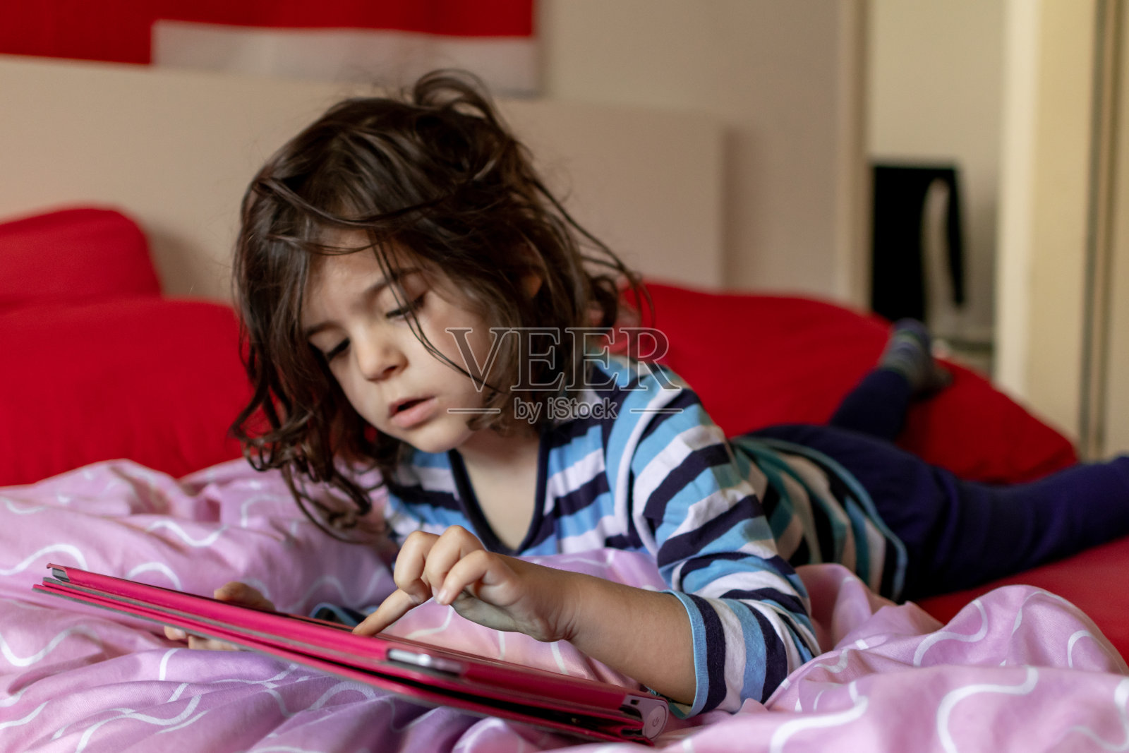 小男孩穿着便服躺在床上玩电子游戏照片摄影图片