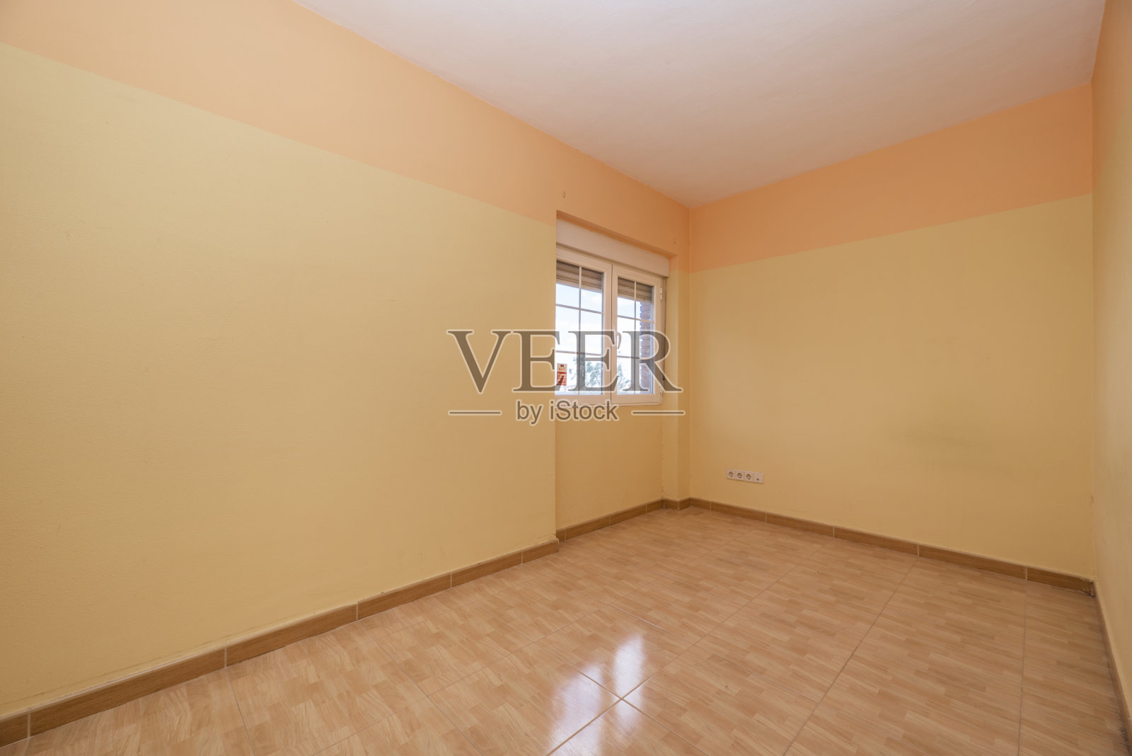 空荡荡的房间,浅棕色的石材地板,两色调的黄色墙壁和白色的铝窗照片摄影图片