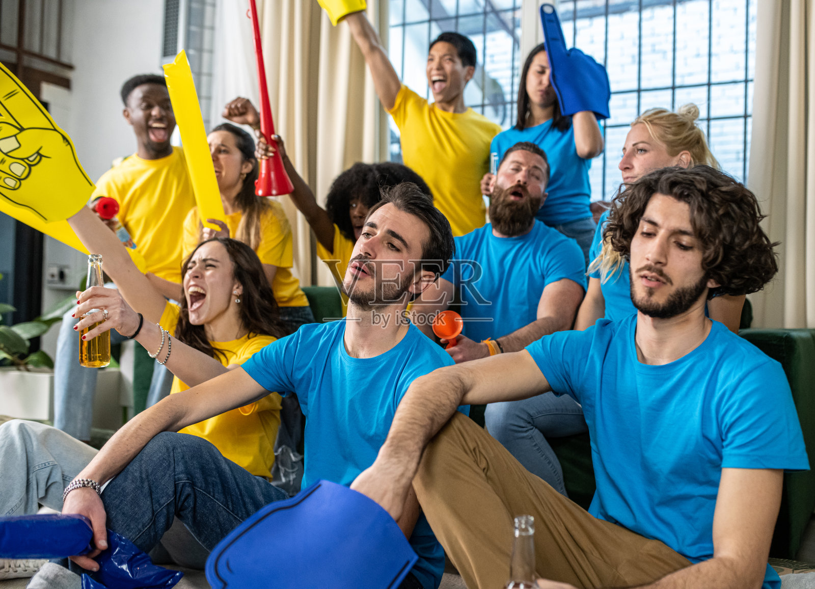 两支不同球队的球迷观看同一场比赛,黄队为胜利而高兴,蓝队为失败而失望照片摄影图片