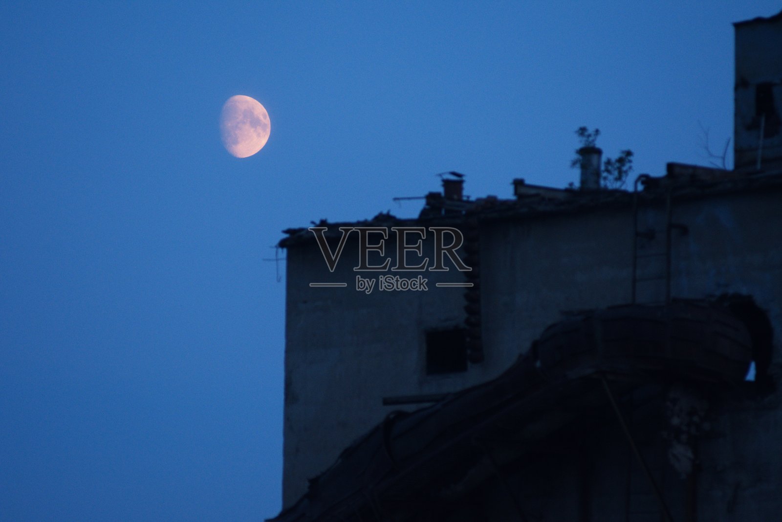 夏夜,一轮黄色的满月悬挂在高塔上照片摄影图片