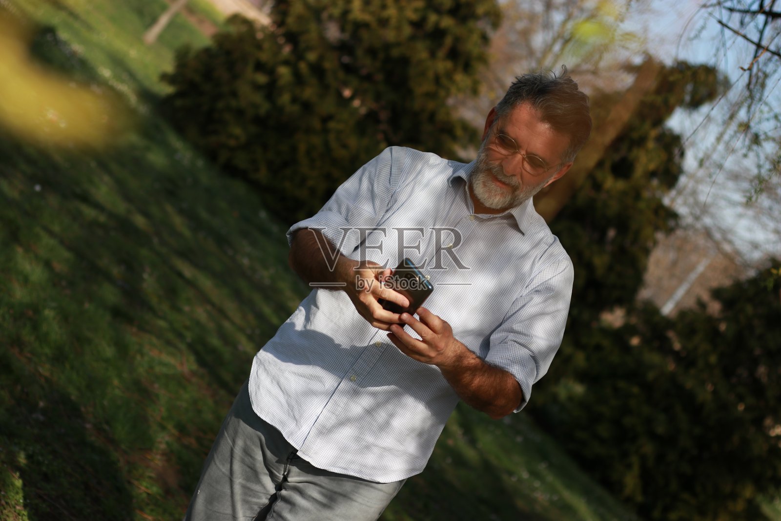 资深男士在大自然中使用电话照片摄影图片