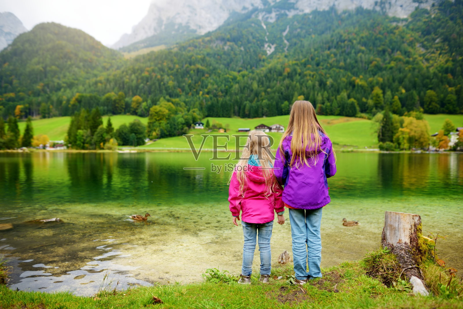 两个小女孩正欣赏着辛辛湖美妙的绿水。德国奥地利边境巴伐利亚阿尔卑斯山令人惊叹的秋景。照片摄影图片