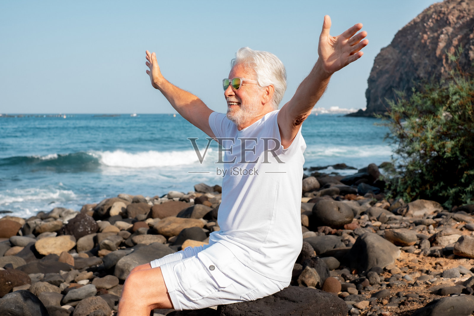 度假退休生活理念在海上,快乐的老人坐在放松的海滩-老爷爷享受自由时间照片摄影图片