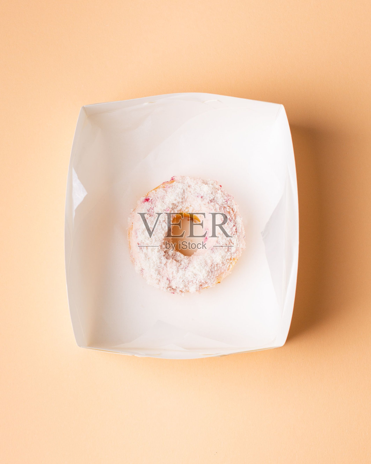 粉色背景上的白色盒子里装着一个甜甜圈照片摄影图片