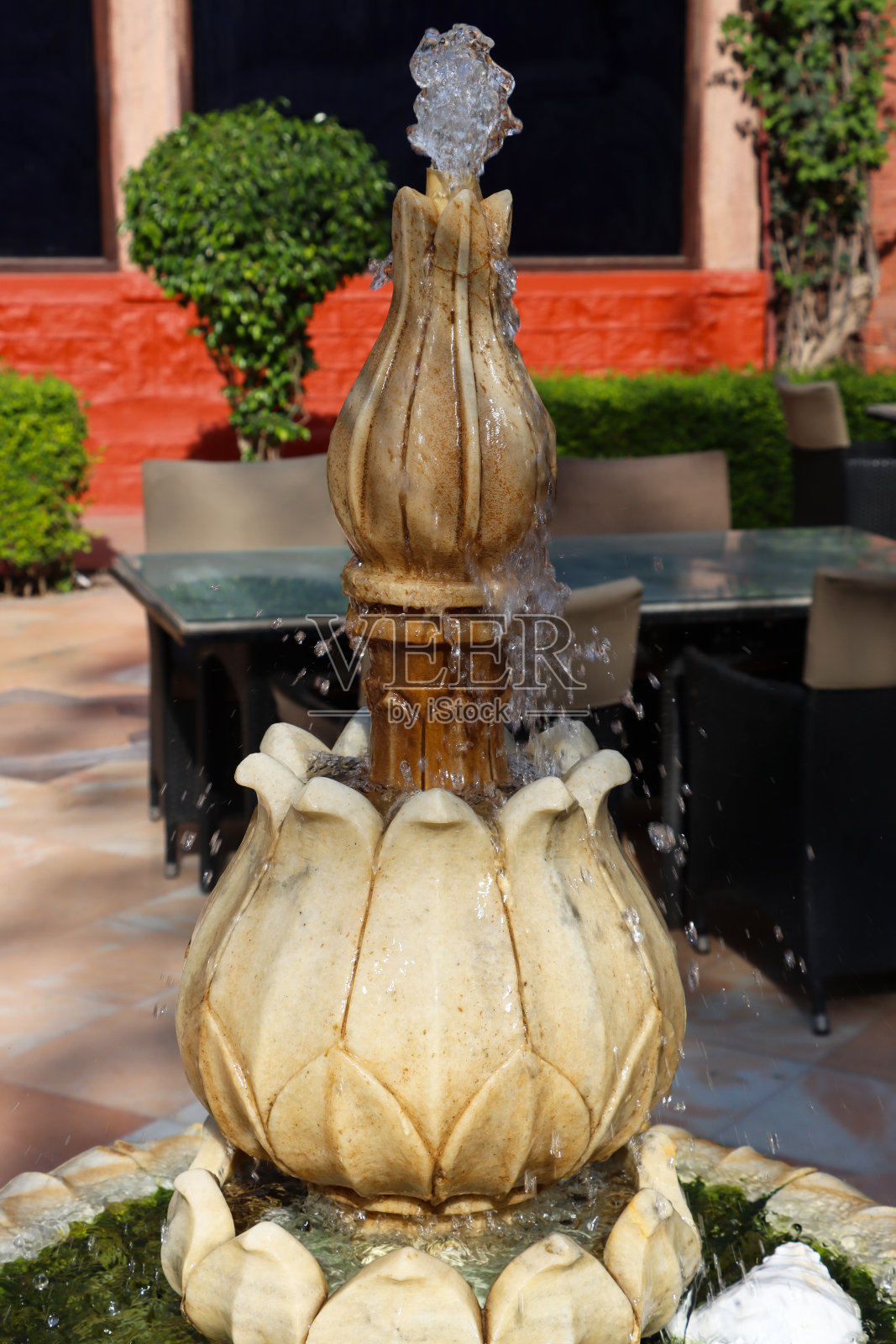 阳光明媚的日子里,公共花园人工池塘喷泉水景,喷泉喷口水流的特写图像,聚焦于前景照片摄影图片