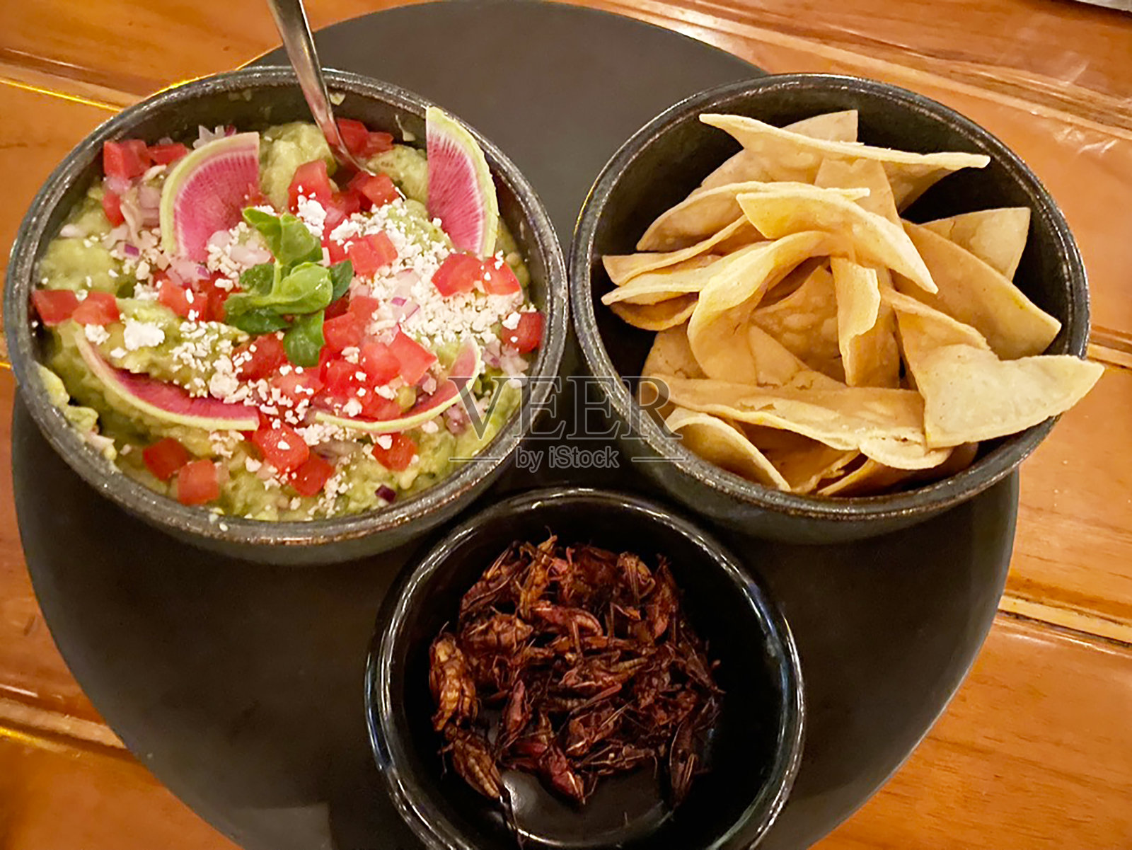 一碗鳄梨酱配上玉米饼片和蚱蜢照片摄影图片