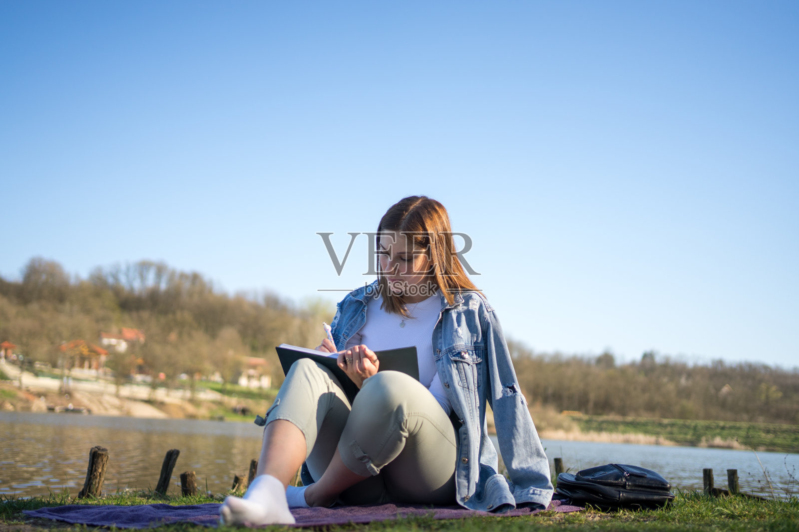 湖边的女人在笔记本上写字。自然的概念。自我反思。照片摄影图片