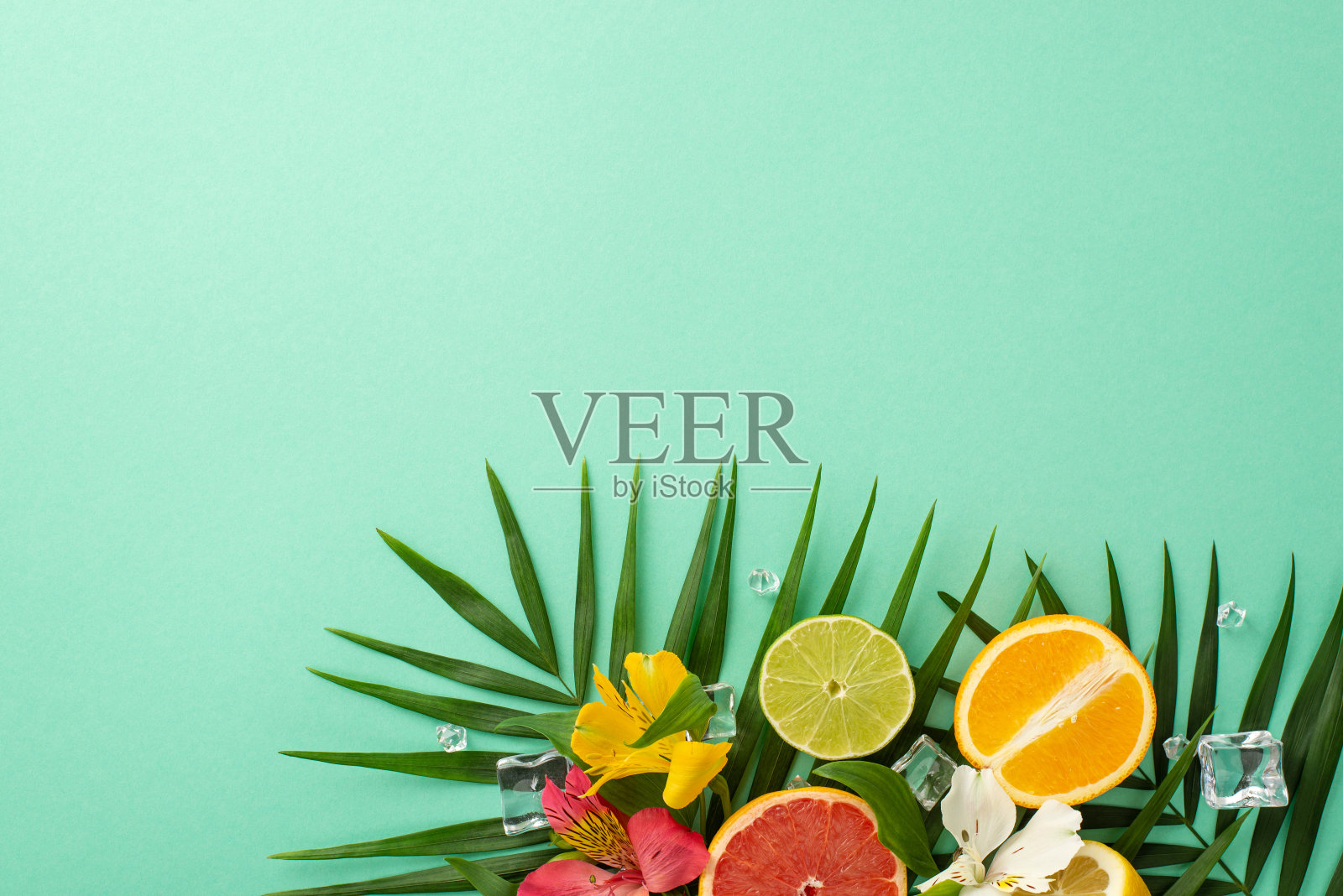 夏季柑橘愉悦概念。顶视图扁平化的alstroemia花与美味的葡萄柚,橙子和柠檬片在柔和的蓝绿色背景与文字或广告的copyspace照片摄影图片