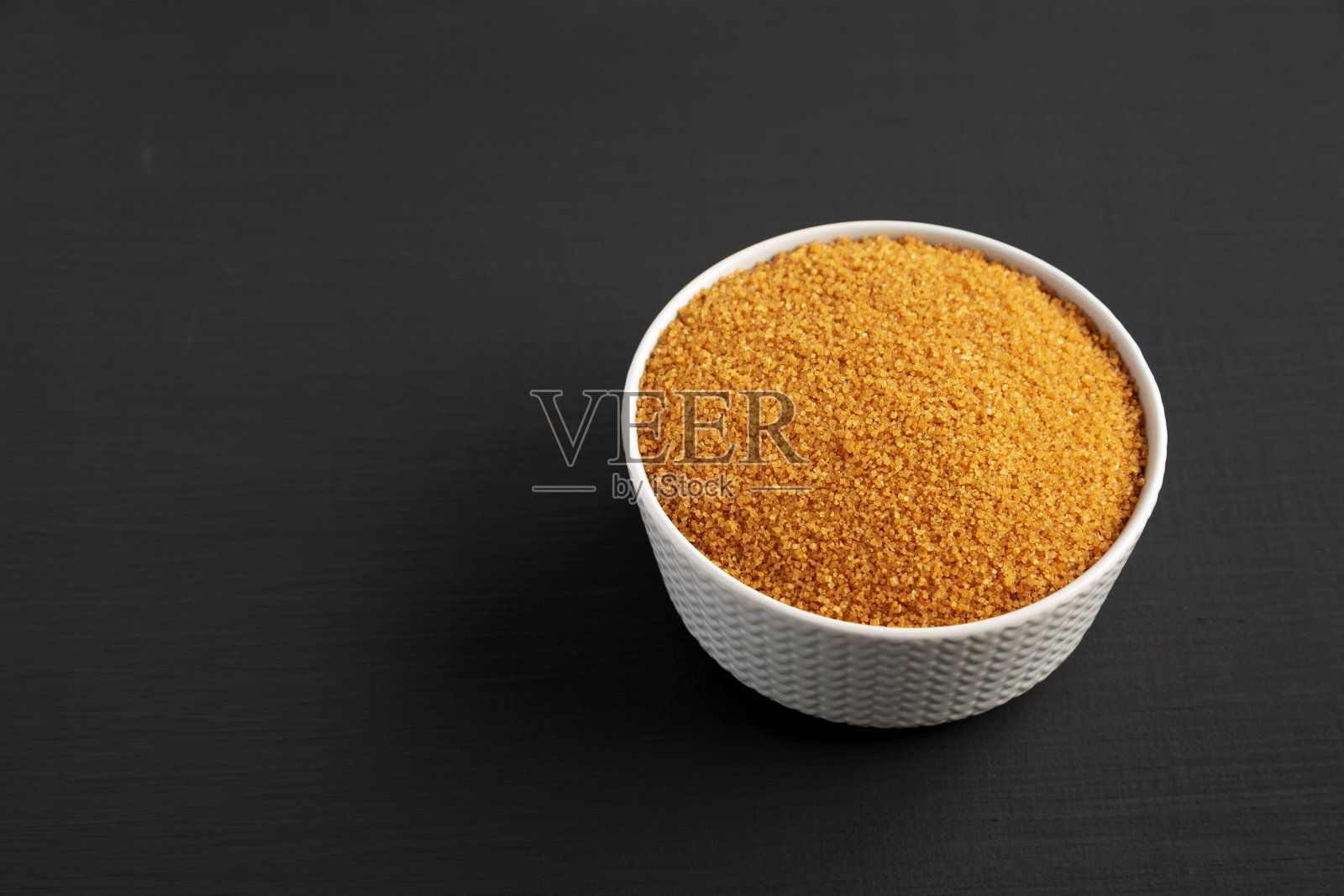 黑面上的棕色德米拉糖碗,低角度拍摄。副本的空间。照片摄影图片