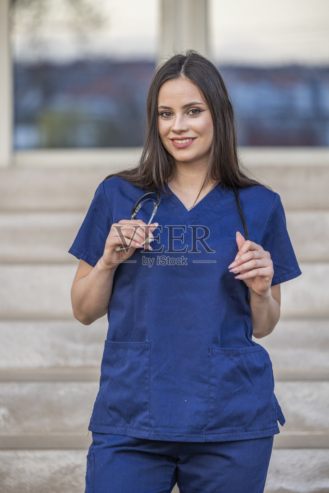 穿着医生制服,脖子上戴着听诊器的年轻医生在户外摆姿势照片摄影图片