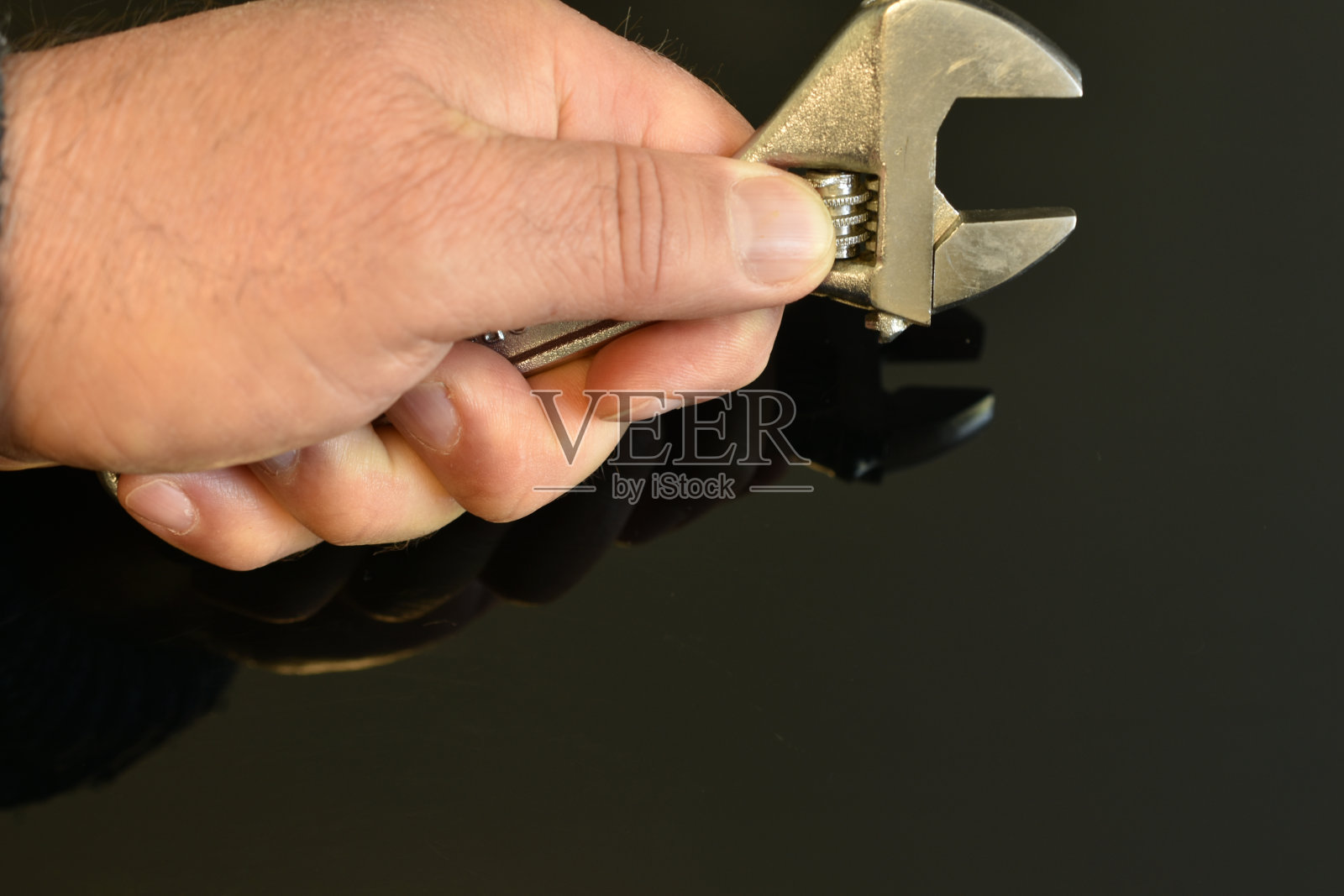 男人的手拿着一把可调节的钳工扳手。照片摄影图片