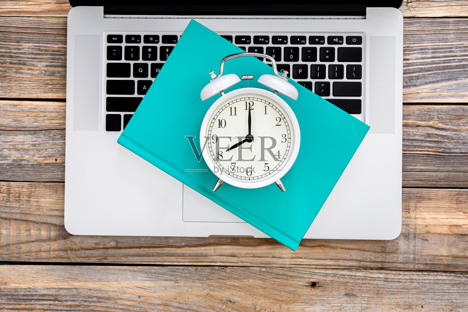 笔记本电脑,书和白色闹钟木制背景,俯视图。照片摄影图片