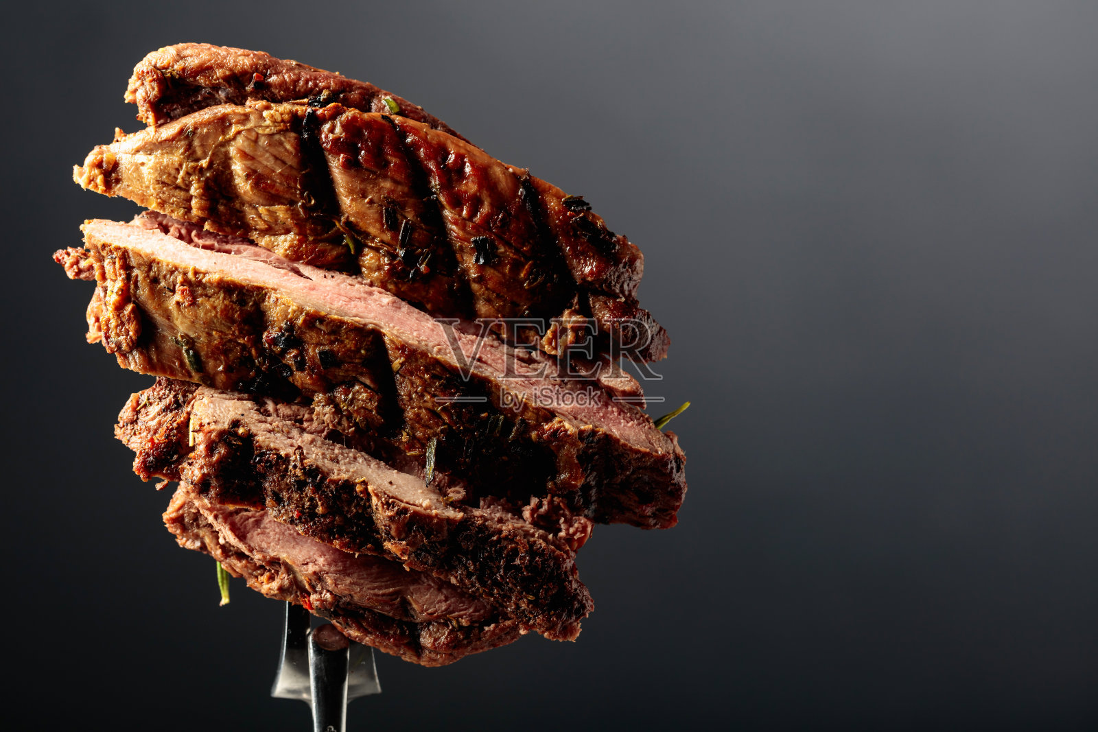 用叉子夹牛排。照片摄影图片