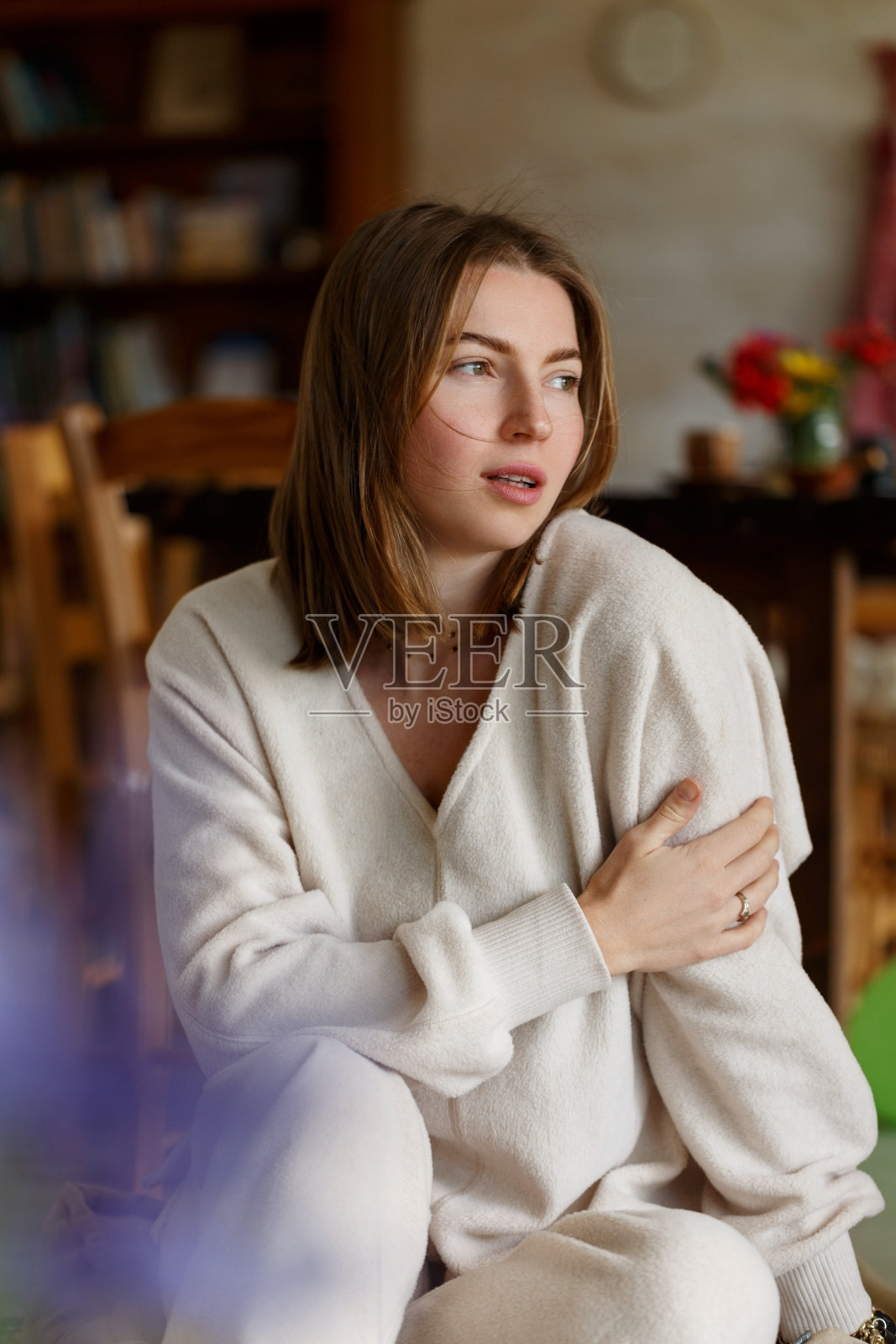 年轻的微笑的女人的脸部分覆盖飞扬的头发在刮风的日子站在家里开着窗户的肖像-无忧无虑的女人。照片摄影图片