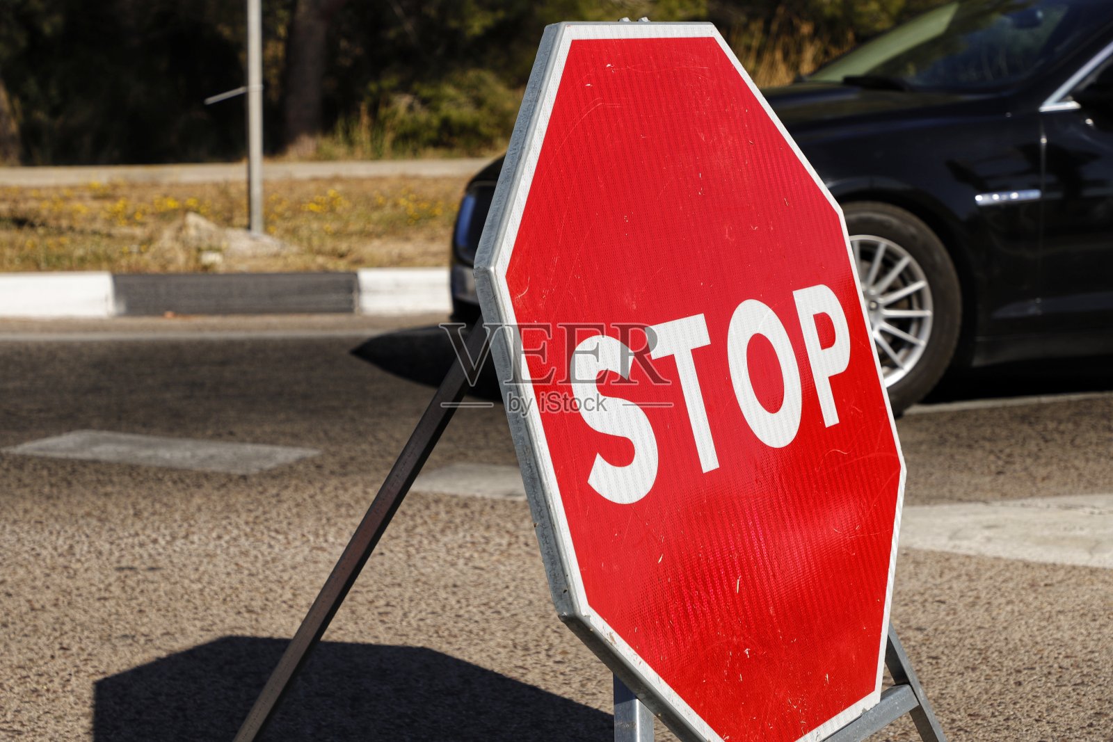 红色停车标志放置在被停车辆旁边的道路上照片摄影图片